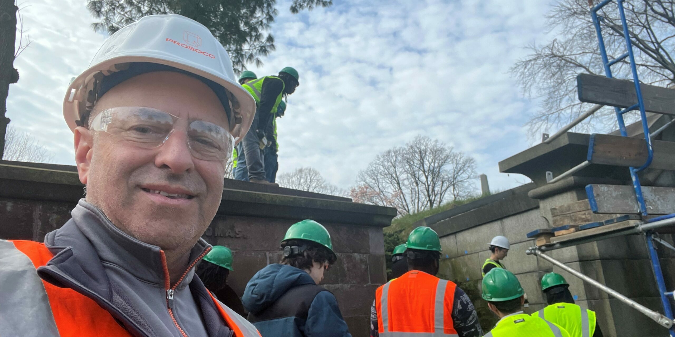 PROSOCO Sales Manager Guy Mazza poses in front of a group of apprentices learning about headstone restoration at Green-Wood Cemetery in Brooklyn.