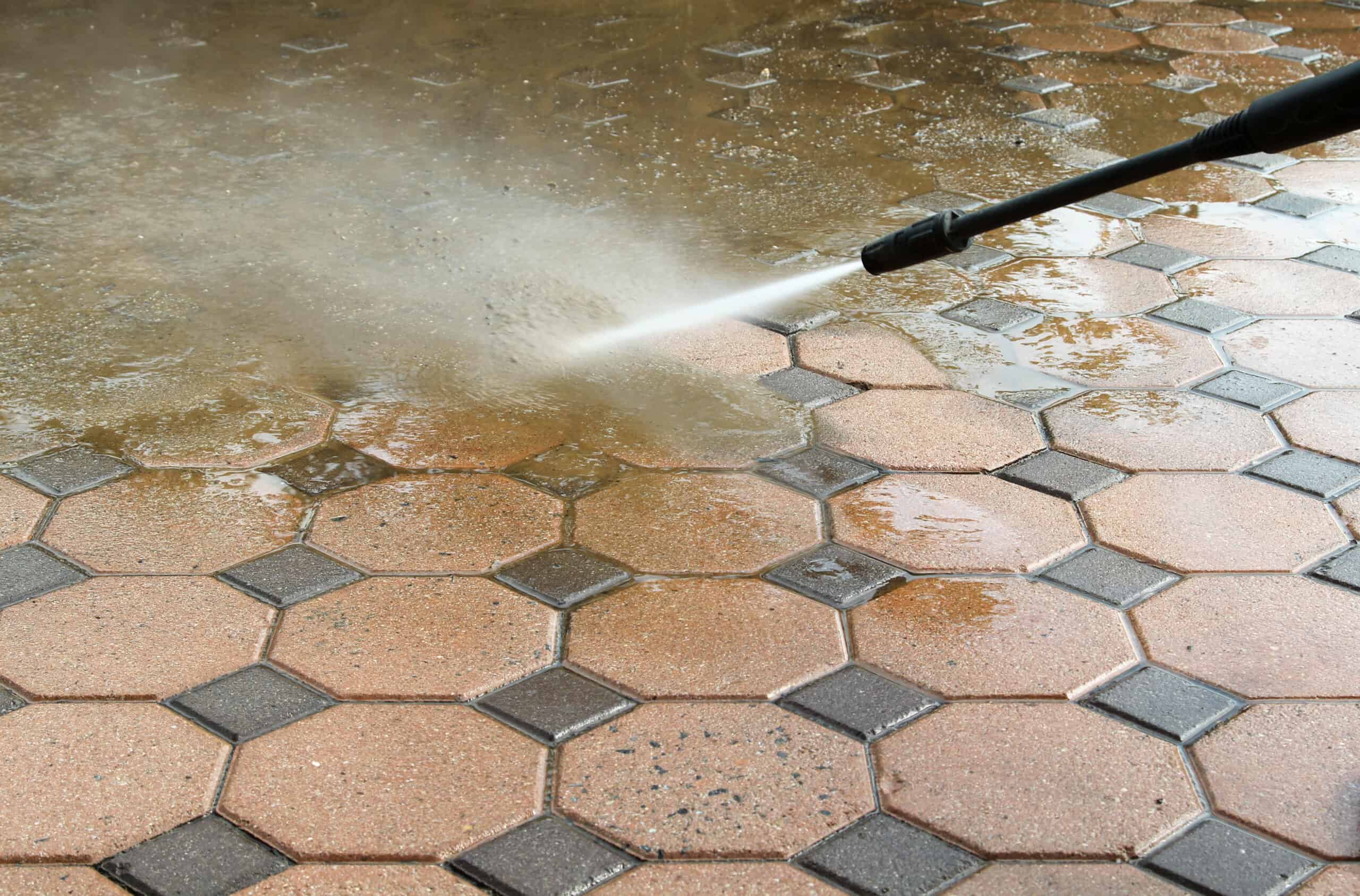 Pressure washing dirt and stains from an outdoor paver surface.