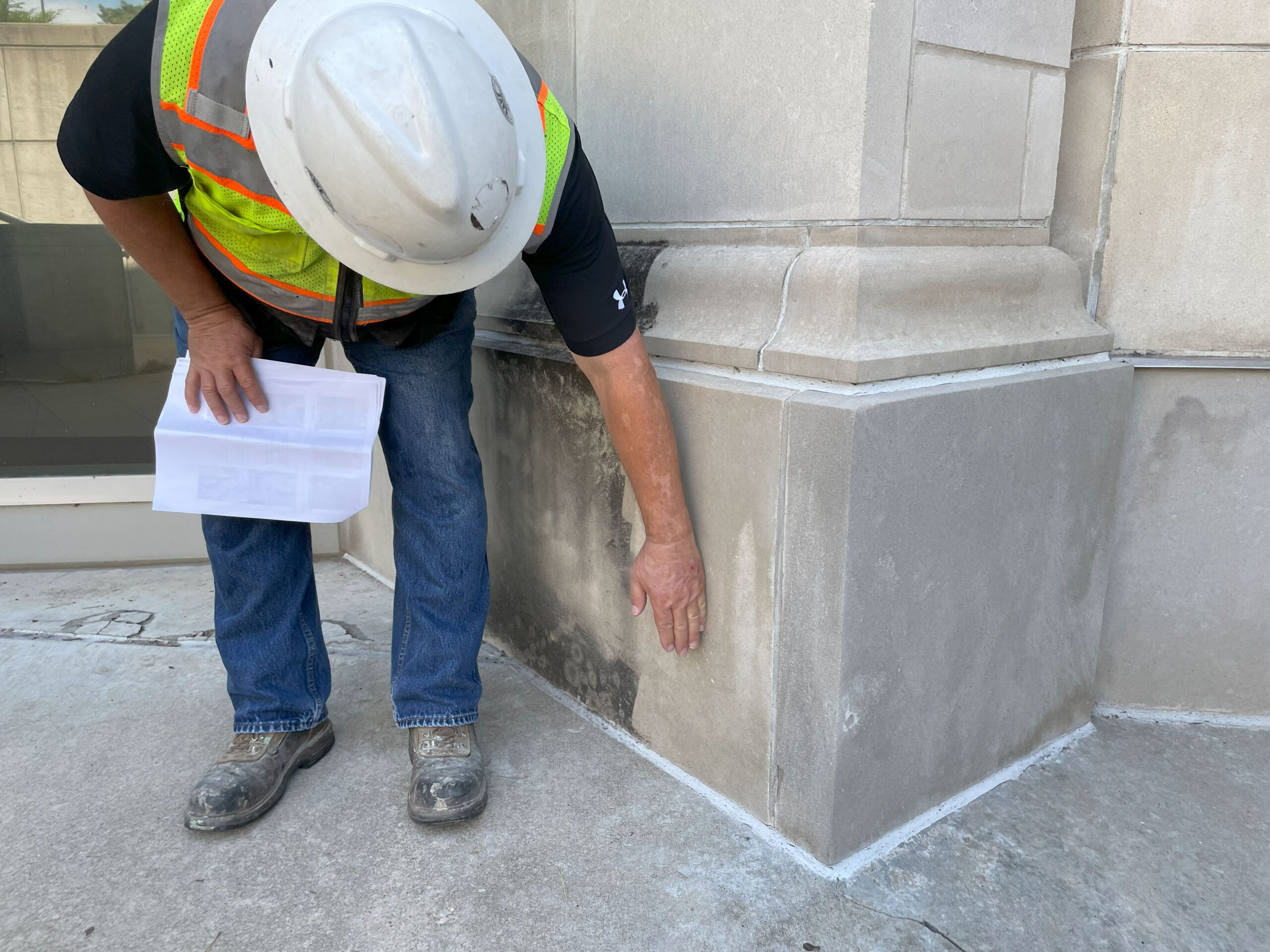 Mike Dickey, Dickey Sales, looks up close at the stain patterns on Budig Hall in Lawrence, Kansas