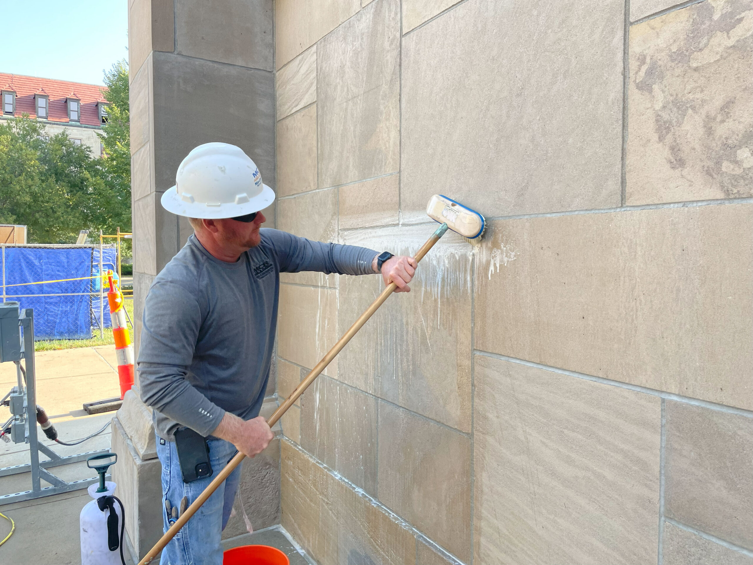 Worker scrubbing an outdoor limestone wall.