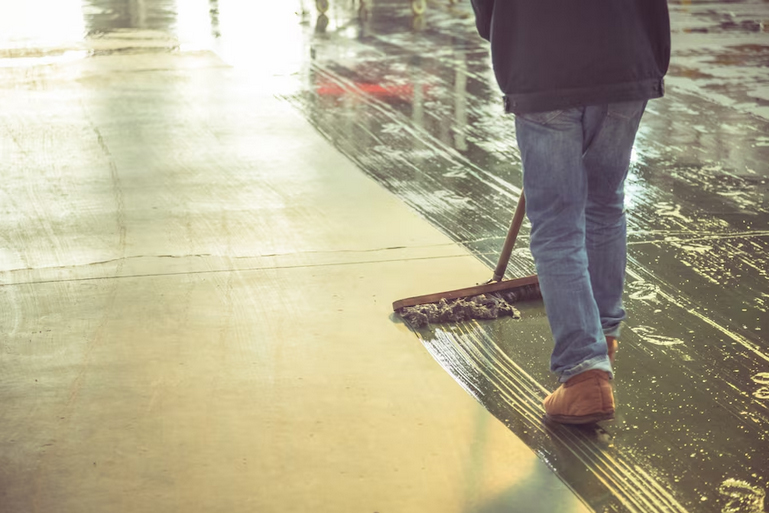concrete-sealer-1 Worker mopping concrete floor with push broom
