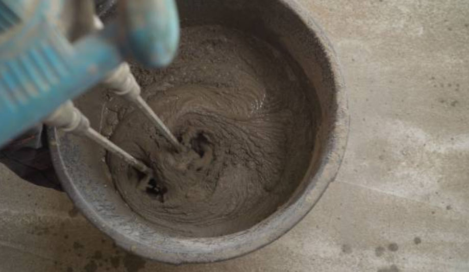 Cement being mixed in a bucket with a drill mixer.