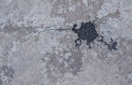 Oil stains and surface damage on concrete prior to concrete resurfacing.