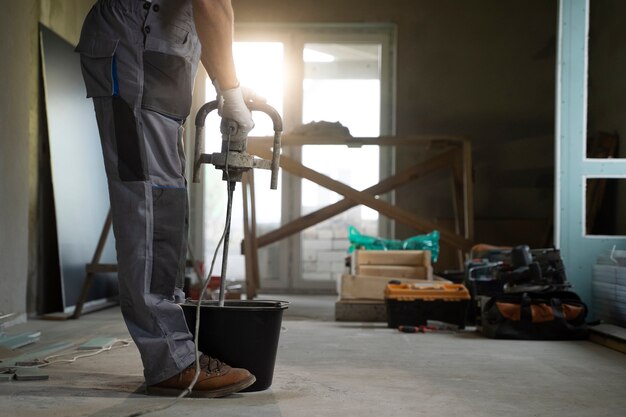 Worker mixes materials for concrete resurfacing on an indoor construction site.
